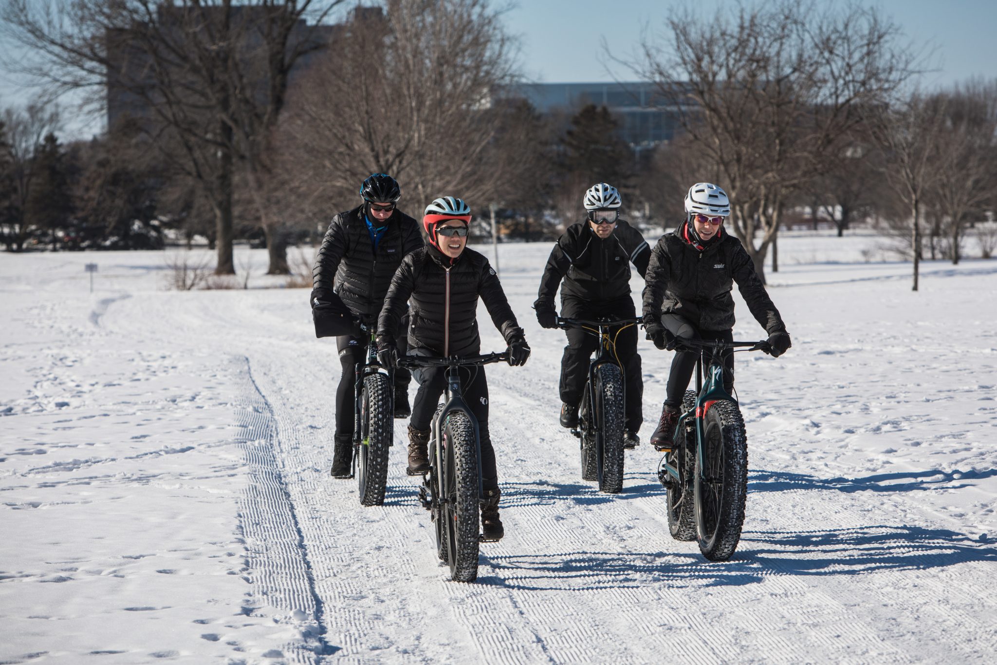 two couples riding fat tire bikes across the snow covered ground