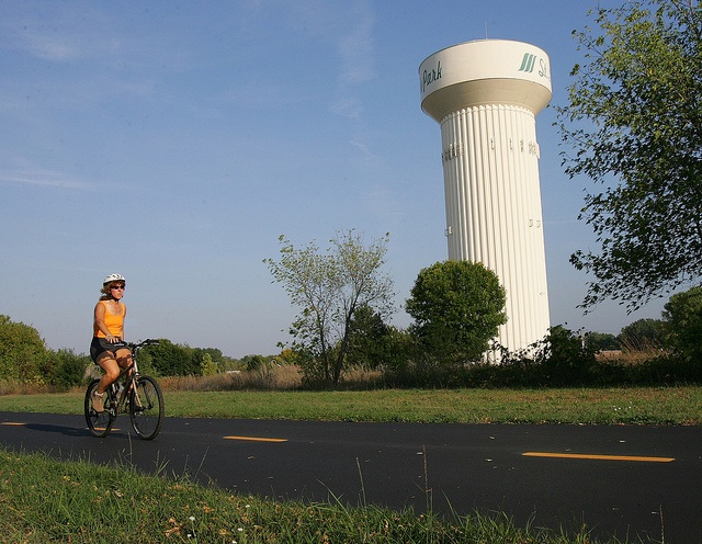 woman biking on a trail near the SLP water tower