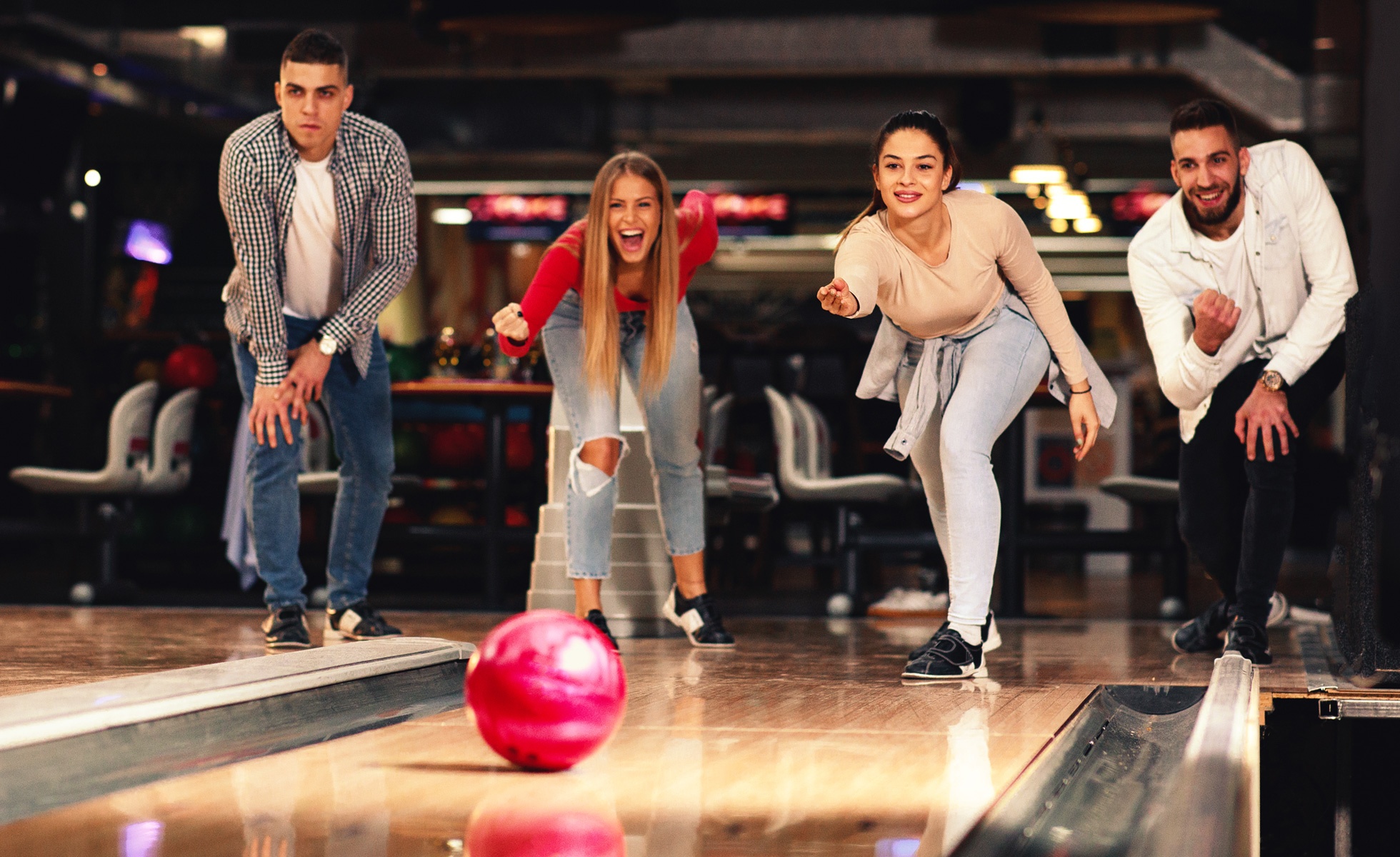 group of friends bowling and watching the ball roll down the lane