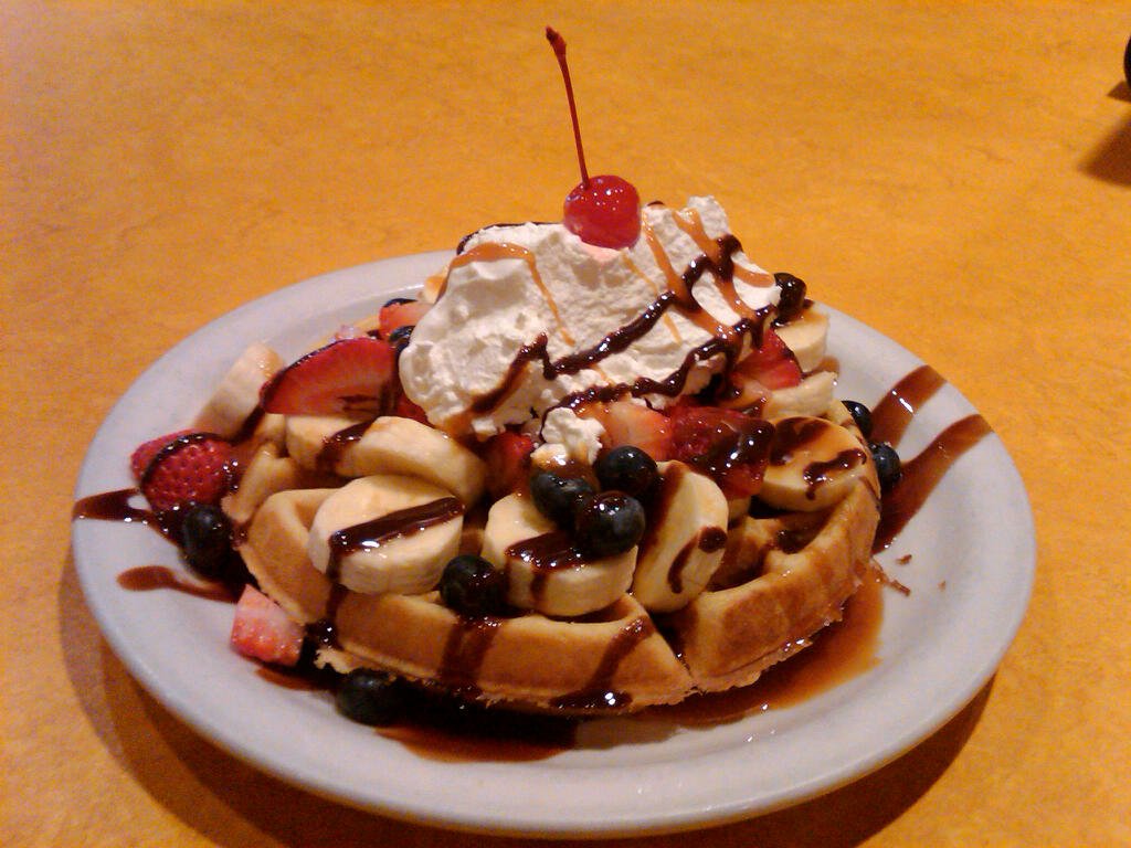 Belgian waffle with bananas, strawberries, whipped cream and chocolate sauce