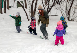 Naturalist leading kids on a walk wearing snowshoes