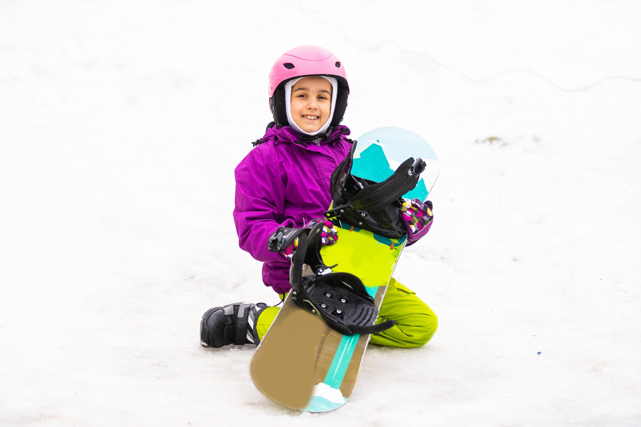 girl sitting in the snow holding her skateboard