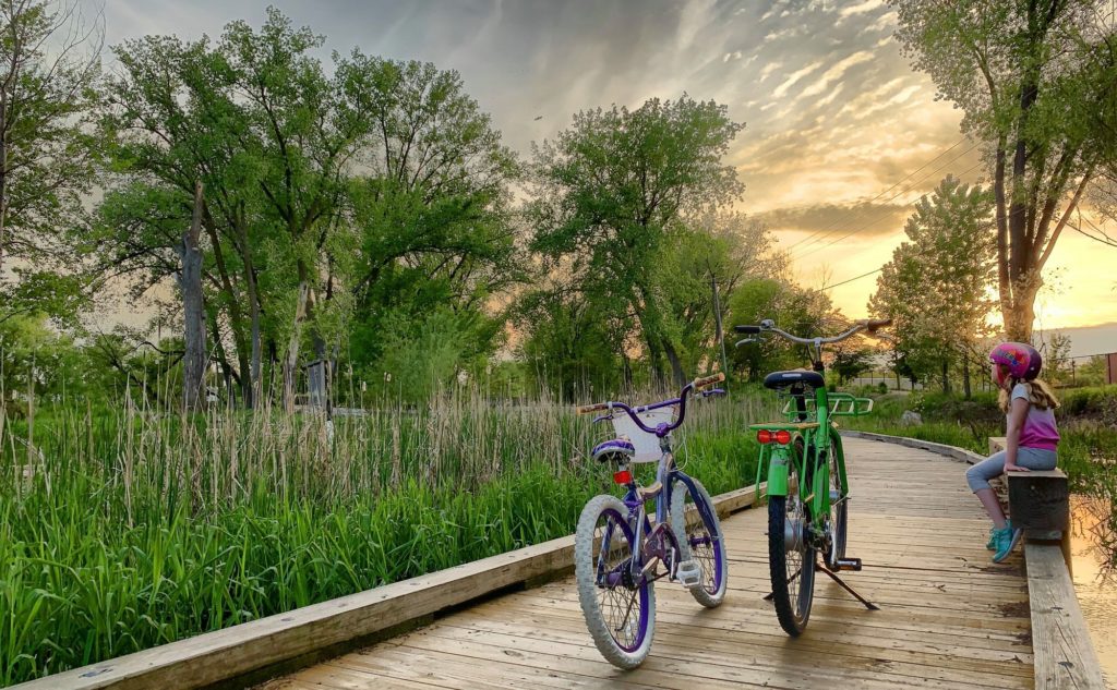 two kids with helmets and two bikes on the Minnehaha Creek Preserve pathway at dusk