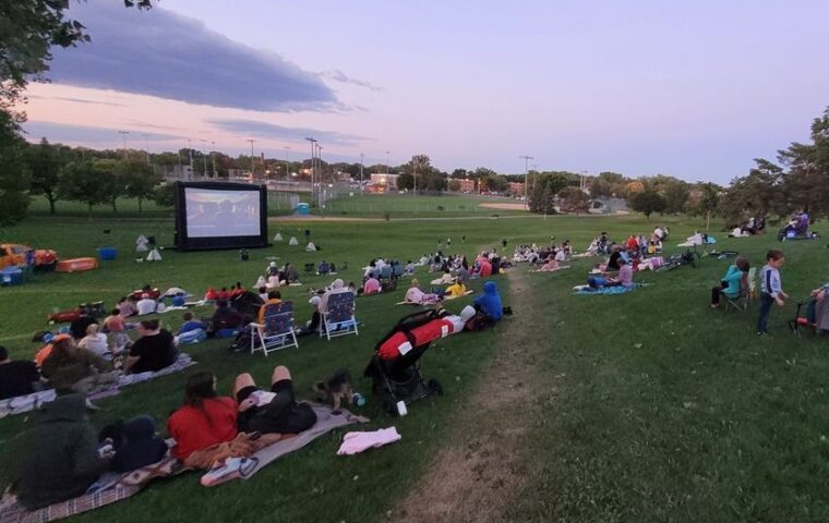 People in a park watching a movie on a portable movie screen