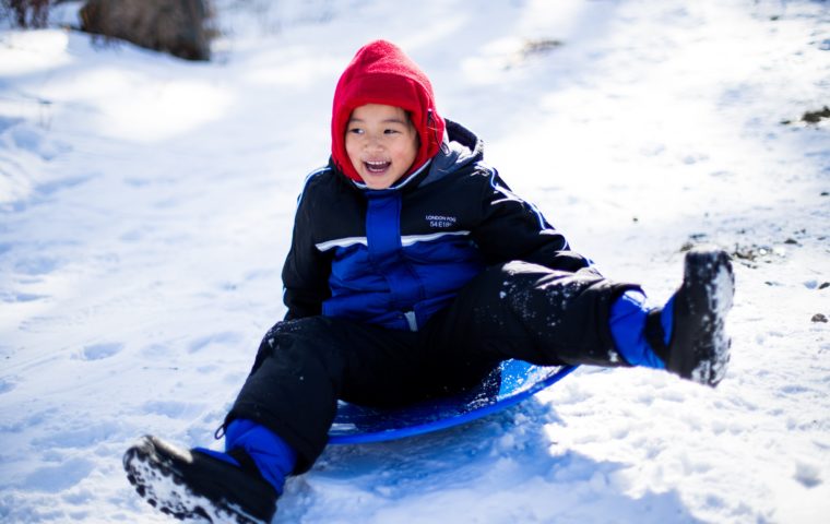 A child sledding down a hill at the Bundled Up! Winter Fun Day