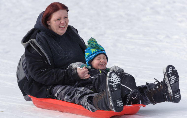 A woman and child sledding at Winterfest