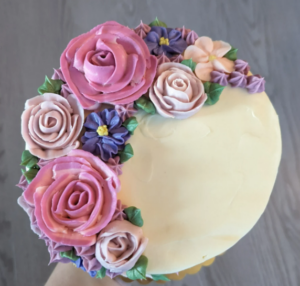 Picture of the top of a cake decorated with pink and purple icing roses